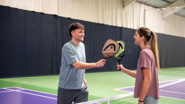 A man and a woman holding pickleball paddles.